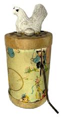 M30 Early 20th century cardboard and tin litho Clucking Hen toy designed to produce a cackling sound when the metal handle is wound. A chalkware figure of a chicken with egg adorns the top, while the litho covering the cylinder depicts children at play with hoops, balloons, roller skates and a May Pole. The original label markings remain on bottom indicating Made in U.S.A. Patented 1936 The Cackling Hen Dist. By AY-WON TOY NOV. CORP. N.Y.C. The cackling sound works well when handle is turned. Some wear and tear by handle from use. 2 ¼ diameter x ~4 ¾ tall.