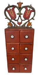 **SOLD** L265 Pennsylvania Folk Art carved and painted eight-drawer Apothecary / Spice Cabinet with original red painted surface with original white porcelain knobs. The top crest features a Folk Art scroll cut out and original polychrome painted heart and tulip motif. The wood is pine with a combination of square head and wire nail construction. Circa 1900-1910. Measurements: Overall height is 26 3/8� tall. Crest is 11� wide x 8 5/8� tall. Case measures 9 &frac12;� wide x 5 5/8� deep x 17 &frac34;� tall. 