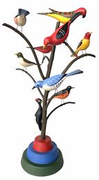 G782 American, 20th Century Folk Art Bird Tree, with nine diffeerent beautiful polychrome painted and hand  carved wooden birds     resting on a steamed and bent branchs in a colorful base This bird tree stands  21"  tall signed M.K. Scheel 