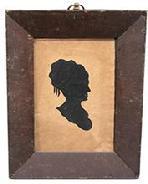 K46 18th century Pennsylvania framed hollow-cut silhouette of a woman against a black fabric background. Original frame and thick, bubbled glass that is secured via small “T” and square-head nails. The very early ring intact on top for hanging purposes also appears to be original. In this type of silhouette, the profile was cut out and discarded. The remaining surrounding paper was then placed against black paper or silk fabric to prominently reveal the wonderful profile. Circa 1790 – 1810. Framed measurements: 7 ½” wide x 7/8” thick x 9 ¼” tall.