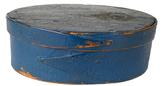 K144 Fantastic mid-19th century New England original blue painted oval pantry box. Steamed and bentwood oval form construction tacked opposing finger-laps secured to the top and bottom with tiny tacks and wooden pegs. The bottoms interior retains an old grungy white painted surface, inside the lid bears natural patina surface. Illegible writing in pencil on bottom of box. Measurements: 6 x 4 ¼ oval x 2" tall 