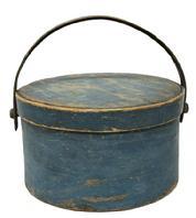 M1129 19th century original blue painted wooden bail handle pantry box with remnants of maker�s stamp (�REUBEN HYDE / WINCHENDON�) on top, center of lid. Sturdy, thick wooden swing handle is attached with large buttonhead wooden pins, and the thick walled, overlapping steamed and bent wood sides are secured with tacks. Clean, natural patina interior. Measurements: 11 &frac12;� diameter (bottom) x 12" diameter (top) x 6 &frac34;� tall (not including handle)