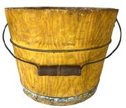 G236 A mid to late 19th century paint decorated bucket from Lancaster County, Pennsylvania. Arched wire bail handle with turned wooden grip. The interior is old natural patina, exterior painted with an overall grained mustard color over a yellow ground having a distinct and unusual diagonal tendril-like combed decoration. Two iron bands secure the staves. In generally good condition having minor imperfections commensurate with age and use. Measurements: 12" diameter x 9" tall.