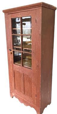 **SOLD** K98 Mid-19th century Eastern Pennsylvania original red painted one door cupboard with applied molding around top and a nice cut out base. The single door is fully mortised and pegged with six original, wavy glass panes in the top over panels below. Square head nail construction. The wood is pine. Clean, natural patina interior.  Circa 1850s. Measurements: 37 &frac14;� wide x 18 &frac12;� deep x 78 &frac14;� tall.   