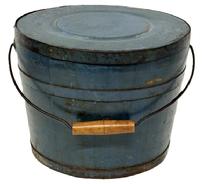 M1144 Identified original blue painted lidded wooden bucket � Stamped on bottom � �Improved and Warranted, by JAMES WHITCHER�.HOOKSET, N H� with arched wire bail handle and turned wooden grip. The thick, solid wood lid is rimmed by a &frac34;� tall metal band secured with hand forged tacks. The interior is old natural patina. Tongue and grooved staved construction held in place with &frac34;� tall metal bands secured with hand forged tacks. Measurements: 11 &frac34;� top diameter x 10� - 10 &frac14;� bottom diameter x 9 &frac14;� tall.