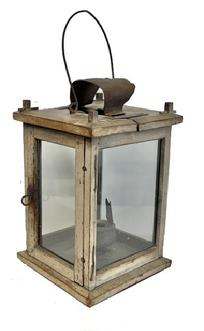 M269 Very rare and unusual, late 19th century Pennsylvania wooden Lantern featuring four glass panels contained within a wooden post and pinned construction frame boasting old oyster white painted surface. Tiny wire loop hinges allow the door to open freely for access to the crudely made circular sheet iron grease/oil lamp rather than a regular candle socket. The grease/oil lamp has its original wick support and hinged lid still intact. There is a hole in the top for ventilation purposes which is covered on the exterior with a bent piece of sheet metal to create a hood that protects the candle flame from wind/rain. There are several make-do repairs to the top. A thick wire bail handle is attached to the top for carrying/hanging purposes. Measurement: 7 square x 10 ¾ tall at corner posts. Overall height is approximately 15 ½ tall including handle in upright position.