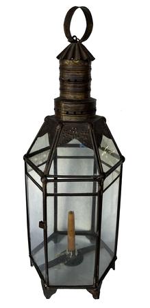 J379 Victorian Era tall glass and metal lantern resting on shaped metal feet. Punched/pierced designs adorn the upper section of metal framing. A crimped metal hood at the very top protects the interior candle from wind/water while punched holes around the conical chimney allow for airflow. A looped sheet metal handle is attached to the top for carrying / hanging purposes. Approximate measurements: 9 ¼� wide x 28� tall. 