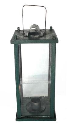 L128 19th century original green painted tall wooden Lantern branded CR on top. Found in Pennsylvania. Lantern features glass panels contained within a wooden pinned and post construction frame. The split glass panel on one side opens freely to access the crudely made metal candle socket. There is a hole in the top for ventilation purposes which is covered on the exterior with a bent piece of sheet metal to create a hood that protects the candle flame from wind/rain. A wire bale handle is attached to the top for carrying/hanging purposes. Measurements: 7 5/8 square x 16 ½ tall not including handle. (Handle is approximately 4 ¾ tall.)