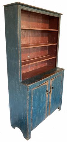 G343 Early 19th century one piece open top Pennsylvania step back Cupboard retaining an old blue surface with red interior. Open top over two plank doors with high cut out feet and nice single bead around doors as well as the open top. Doors open to a clean, natural patina interior, with original shelves for added storage. Square head nail construction. Circa 1800.