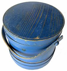 **SOLD** RM1389 Excellent, identified New England sturdy wooden firkin in beautiful original blue painted surface. Signed �John Bushman Jr.� inside the lid, and the initials �J.B.� on the bottom. Thick-walled tongue and groove softwood staved sides secured by tapered lap joint wood bands held in place with copper tacks and one tiny staple at the end of each band. The bent wood swivel handle is secured with wood peg attachments. Natural patina interior. Measurements: 9 5/8� diameter (top) x 10 1/8� diameter (bottom) x 9 ½� tall. Overall height with handle raised is ~13 ½� tall.