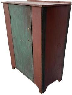 F534 Mid 19th century PA single door storage cupboard. Door is one single board wide with nice cut out at base. It has half inch beaded molding on both sides of door and outer front corners. It has all square head nail construction. In early red and teal paint over the original red. Ca 1840-1850.