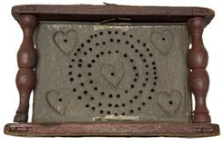 M307 Late 18th to early 19th century Wooden Foot Stove / Foot Warmer bearing original red painted wooden frame, punched tin panels and hand-forged twisted iron bale handle for easy carrying. The fully mortised and pegged wooden frame with turned post corners secures the tin heating chamber that features great folk art punched tin panels bearing punched heart decoration. Retains its original removable rectangular sheet metal cup inside to hold the coal / ashes.  Measurements: 7 5/8� x 9� x 5 &frac34;� tall.  