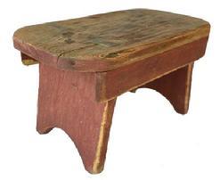 F465 Early 19th century Lancaster County, Pennsylvania mortised stool, in old red paint, high arched cut out sides, with splayed legs and drop aprons on both sides. One board pine wood, square head nail construction.