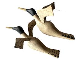 L36 Pair of miniature hand carved flying duck decoys bearing original painted surfaces and delicately thin carved wings. Solid wood. Carver unknown.  One measures: 5 ½ wingspan x 6 ¼ long x ~2 tall and the other one measures 6 wingspan x 7 long x ~3 tall.  