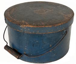 J199 Exceptional early 19th century New England bail handle pantry box retaining original blue painted surface. Lid impressed "HOLMAN, HEYWOOD & CO MANUF'S, FITZWILLIAM DEPOT, N.H." Heavy construction with overlapping steamed and bentwood sides secured by small copper tacks.  Original wire bail with wooden handle that retains remnants of blue paint and dark patina from years of use. Interior retains its natural patina surface. Measurements: 11 ¾� diameter x 6 ¾� tall