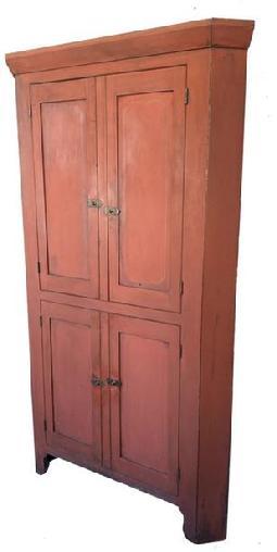 G442 Mid 19th century center county Pennsylvania four door Corner Cupboard, with original red paint with mustard pin stripping around the corners of the panel in the door. , with old natural patina interior. High cut out base, two large panel doors over two panel doors below, mortise and pegged construction, with applied molding around the top of the cupboard. circa 1840