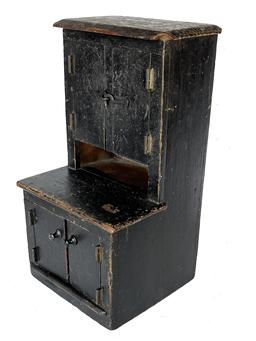 J386 Charming 19th century child's stepback cupboard in original black painted surface. Two door over two door configuration, with internal shelving in the upper portion. Small square head nail construction. Measurements:  6 5/8� wide x 6 ½� deep (with the top portion of the cupboard being stepped back 3�) Overall height is 12 ¼� tall.
