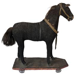 **SOLD** K1750 Early 1900s Mohair Covered Pull-Toy Horse on wooden platform with metal wheels. The solid wooden horse features hand carved and painted nose/mouth and hooves, tack eyes, leather ears, a very well-worn mohair covering with natural horsehair mane and tail and remnants of the leather tack. The wooden platform retains original red painted border beneath a heavy patina and four original metal wheels that move freely. The horse is mortised into the base below each hoof. Measurements: Base is 15 long x 5 wide. Overall height is 16 ¾ tall.   