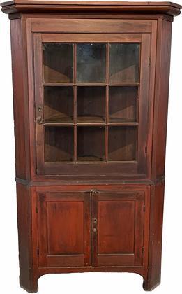 H262  Berks County, Pennsylvania original red painted two-piece nine window lite corner cupboard with two blind-panel doors on bottom. Reeded molding throughout. Nice painted surface, never over painted. High cut out foot. Original wavy glass in top door. Interior retains an original red-wash surface. Circa 1820  1850. Measurements: 78 ½ tall and takes a 31 ½ corner  