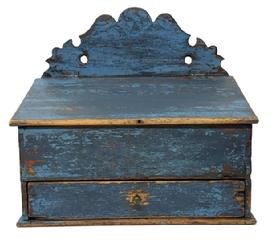 M1111 Early 19th century blue painted wall box with decoratively cut out back, hinged lid and drawer below. The old blue paint is over its original paint decorated surface.  Dovetailed case and drawer � with both having divided interiors. Small square head nail construction. Circa 1840�s. Measurements: 12 &frac34;� wide x 7 &frac34;� deep x 6 &frac12;� tall (front) x 14� tall (back).