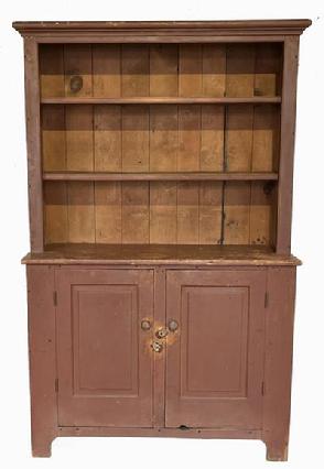 H95 Early 19th century Pennsylvania one piece open top stepback cupboard in dry, original red painted surface featuring open shelves over two beautiful, raised panel doors. Upper shelves boast double beaded edges along the front. The two fully mortised and pegged doors are raised panel inside and out and open to a clean, natural patina interior with shelf for added storage.