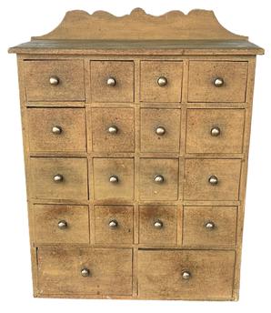 J126 Late 19th century Pennsylvania original Mustard painted apothecary / spice cabinet featuring an unusual 18 drawer layout with brass pulls. The drawer stretchers are mortised into the ends. A decorative cut out backsplash adorns the back while a chamfered edge surrounds the other three sides of the top.  Measurements: 21 wide x 8 ½ deep x 27 tall (center of back). The front measures 24 tall.  