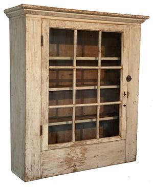 200 Early 19th Century hanging flat wall cupboard from Western Pennsylvania in original white paint, having a single door with 9 window-lites and a small chamfered molding around the top.  The door is full mortised and pegged with early wavy, bubbled glass.  There are three reverse graduated shelves inside (Top to bottom: 7 deep, 6 ¾ deep & 5 ½ deep) which allows better access to the inside bottom of the cupboard.  All square nail construction. Measurements: 39 tall x 33 ¼ wide case (35wide at molding) x 9 ½ deep (10 ¾ deep at molding)