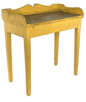 J416 Virginia wash stand with applied decorative cut out gallery in old mustard paint. The apron and Hepplewhite tapered legs are mortised and pegged. Gallery bears a chamfered edge along the bottom sides where it is attached to the stand. Square head nail construction. The wood is yellow pine. Circa 1850�s. Measurements: 30 ¾� wide x 16 ¾� deep x 29� tall (front) x 33 ¼� tall (back). Apron to floor measures 23 ¾� tall. The one-board top is 15 ¾� wide.