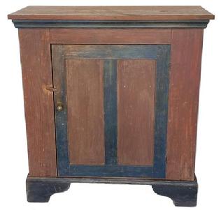 G625 Wonderful mid 19th century one door storage cupboard from Sussex County, Delaware in the original red and blue paint with a tall black painted applied base. Yellow pine, square nail construction. Original cast iron hinges. Applied molding around the underside of top which is also painted blue.. Circa 1850s. 