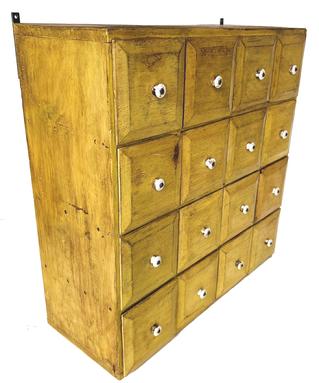 H100  19th century Pennsylvania apothecary with 16 drawers boasting chamfered drawer fronts and original porcelain knobs in original mustard painted surface. �Philadelphia, Pennsylvania� is written on side of one of the drawers.  Measurements: 23� wide x 23� tall x 9� deep