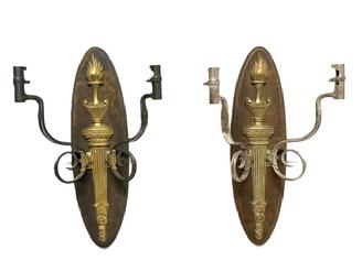 RM1647 Pair of hanging wall sconces featuring a brass flaming torch motif mounted on an oval wooden backplate with each of the candle arms constructed of bent and curled, US marked Bayonets. One of the sconces features two bayonets with nickel plated surfaces (~11 ½ wide) and the other features two bayonets with blued surfaces (~12 ¼ wide). The locking ends of the bayonets, meant to attach to rifles, becoming the candle sockets for the sconces. Backs measure ~5 ¼ wide x ~19 tall.