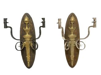 RM1647 Pair of hanging wall sconces featuring a brass flaming torch motif mounted on an oval wooden backplate with each of the candle arms constructed of bent and curled, �US� marked Bayonets. One of the sconces features two bayonets with nickel plated surfaces (~11 &frac12;� wide) and the other features two bayonets with blued surfaces (~12 &frac14;� wide). The locking ends of the bayonets, meant to attach to rifles, becoming the candle sockets for the sconces. Backs measure ~5 &frac14;� wide x ~19� tall. 