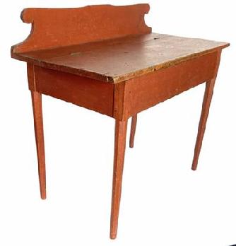 G866 NEW ENGLAND RED PAINTED LIFT LID WRITING DESK, circa 1820 featuring shaped backsplash, hinged lid concealing shallow well, and pencil post legs with beveled-edge profile, period pencil inscriptions to underside of lid. Retains an original red-painted surface.