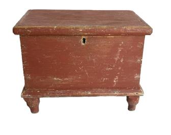 M148 Early 19th century miniature Blanket Chest retaining original dry red painted surface. Six-board pine with dovetailed case and applied moldings to top and bottom, resting on turned feet that are mortised through the bottom. Square head nail construction. Natural patina interior with the name Kay Floyd written in several areas inside. Circa early 1800s.