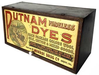 J192 General Store Advertising display cabinet for Putnam Dyes. This double-sided display cabinet is made of wood with colorful panels on the front and back. The door lifts to reveal an instructional label that identifies how to achieve �popular shades made by mixing Putnam fadeless dyes.�.