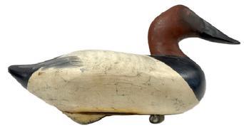 L493 Canvasback Hen Decoy - Signed and dated on bottom "R. Madison Mitchell 1954". Original weight and ring are intact on bottom of decoy. Imprinted metal tag identifying a presumed former owner, J. W. Mowery 435 N. Mary Street - Lancaster PA also remains intact on bottom. Original surface with early age crack to body. Approximate measurements: 15 long x 6 ½ wide.