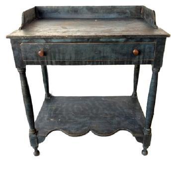 M94 Early 19th century New England Sheraton blue paint decorated open Washstand bearing original blue painted surface with black smoke decoration. Features an applied dovetailed gallery with shaped ends, a full-sized dovetailed drawer, a shelf below with a decorative shaped front edge and turned legs. All original. Square head nail construction. Circa 1820s-1840s