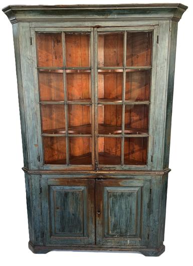 L19 Exceptional 19th century Pennsylvania one piece blue painted corner cupboard with two, 8-windowlite glass doors up top over two raised paneled doors below. Glass doors, featuring the original wavy glass, open to reveal butterfly shelves and a beautiful bittersweet painted interior. Wonderful, applied molding surrounds the top and cupboard rests on an applied cut out base. All doors are fully mortised and pegged. Case is square head nail construction. Measurements: 53 x 36 x 80 ½ tall. 