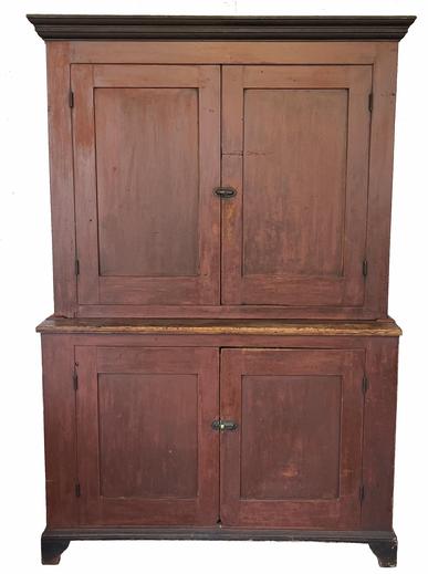 H955 Pennsylvania 19th century two piece painted pine Dutch Cupboard retaining its old dry red painted surface. Nice, applied bracket base around the bottom and applied molding around the top feature an early black painted surface. All four paneled doors are fully mortised and pegged. The interior shelves in the upper section have double plate grooves along the back edge of each shelf. The original metal catch behind the upper doors remains intact � and is typical of those found in the Lancaster, Pennsylvania area. Natural patina interior. Measurements: 50 5/8� wide (top) x 18 ¾� deep (waist) x 74 ¾� tall