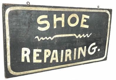 H942 Late 19th century Pennsylvania hand painted wooden Trade Sign advertising "Shoe Repairing." White painted lettering, on a single board with a white border and a shoestring design in the center on a black background. Single sided.