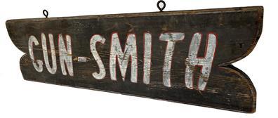 *SOLD* J428 Double sided wooden Trade Sign with fish tail shaped cut out ends advertising "Gun-Smith". The letters are hand painted in white paint with red outlining on a dark gray background. There are remnants of red and white pinstripe outlining surrounding the edges on both sides of the sign. Original old iron eye hooks used for hanging purposes remain on the top side of the sign. Measurements: 34� wide x 10� tall x ¾� thick.
