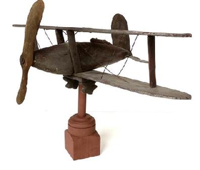 Folk Art wooden biplane with traces of old gray. The plane's body, The propeller, wings and wheels all carved from sections of wood. The tail fin original sheet tin with traces of original red star. Early 20th century. very good original untouched condition Complete with stand for displaying .