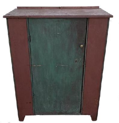 F534 Mid 19th century PA single door storage cupboard. Door is one wide, single board with nice cut out at base. It has half inch beaded molding on both sides of door and outer front corners. It has all square head nail construction.  In early red and teal paint over the original red. Circa 1840-1850. Dimensions are 32 3/4� wide x 17 1/4� deep x 41 3/4� tall