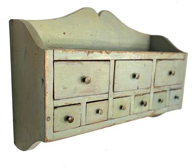 G911 Late 19th century Pennsylvania original  painted hanging spice chest apothecary with a very unusual design featuring 3 drawers over 6 drawers. The raised sides and cutout on the tall back board create a shelf area along the top and there are five early metal hooks along the bottom which add to the diversity of the layout.  Measurements: 23 1/2" wide x 7" deep x 16" tall