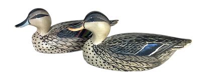 K1679 Two miniature duck decoys carved by Oliver Tuts Lawson (1938- ) of Crisfield, Maryland. One is a miniature Mallard Hen (8 ¼ long x 3 wide x 3 ½ tall) and the other is a miniature Pintail Hen (8 ¼ long x 3 wide x 3 ¼ tall). Both are balsa wood bodies with slightly turned heads and original painted surfaces. Paper label from the Duck House, Rumbley, Maryland remains intact on the underside of Pintal.  