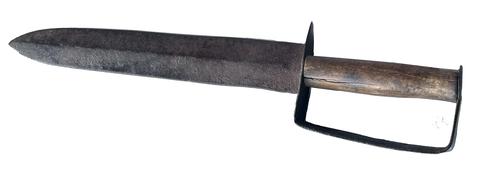 RM1499 Civil War Confederate D-Guard Bowie Knife. An impressive knife made from a worn-out file with a long single-edge blade with clipped point. The D-guard is made of heavy wrought iron with a turned down quillon. The metal has a nice patina, and the remnants of the wooden grip have toned nicely with age. Though crude in construction, the knife is still a well-made example of this highly collectible style of Confederate edged weapon. Measurements: 15 3/4" long x 3 1/4" wide at handle area