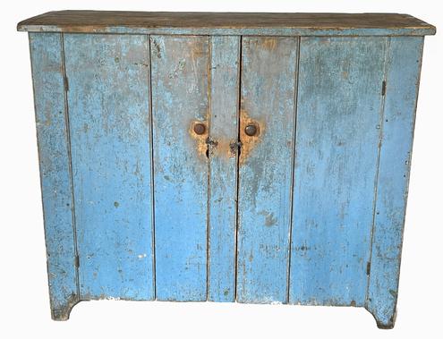 **SOLD** K1722 19th century New England original blue painted two door storage cupboard - identified on bottom from upstate New York (Courtland County NY). The cupboard boasts its original dry blue painted surface with half-moon cut out ends and beaded edges on corners and around the doors. Doors open to reveal natural patina interior with shelving for added storage options. The wood is pine with square head nail construction.  Circa 1850s. Measurements: 52 ¼ wide x 18 deep x 43 ½ tall. The wood is 1 thick.   