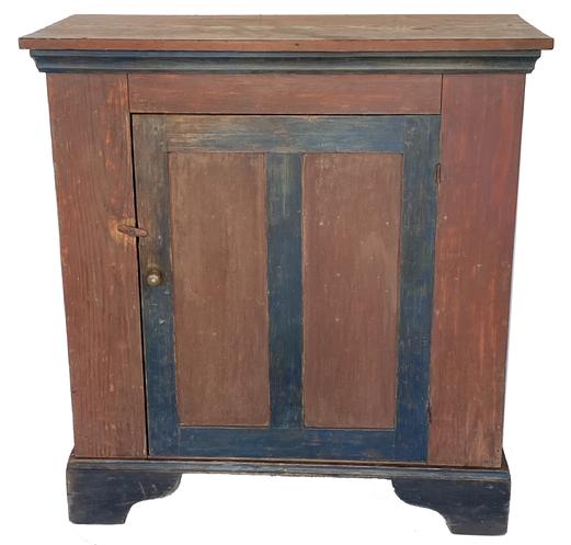G625 Wonderful mid 19th century one door storage cupboard from Sussex County, Delaware in the original red and blue paint with a tall black painted applied base. Yellow pine, square nail construction. Original cast iron hinges. Applied molding around the underside of top which is also painted blue. Clean, natural patina interior with shelves. Circa 1850s.   Measurements: 40 1/4� wide x 19� deep x 43� tall