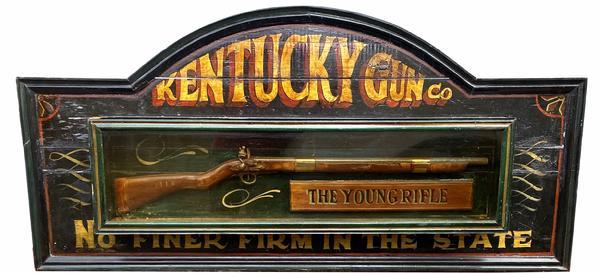 G331 Kentucky Gun Co. trade sign,Second half of the 20th century, sign is made of painted wood, with faux rifle behind glass case, with gold and red lectern on black back ground