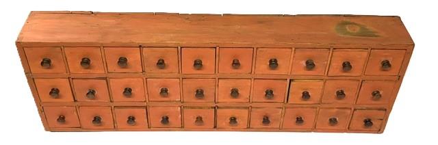 M1140 19th century New England Apothecary featuring 30 dovetailed drawers retaining the original dry, salmon painted surface. Dovetailed case with square head nail construction drawers and mortised stretchers. One of the drawers retains handwritten dates along its top edges � �March 2nd 1864� and April 30th 1868�. This versatile piece can be hung on the wall or used on a sturdy flat surface. Measurements: 44 &frac14;� wide x 6� deep x 15� tall. 